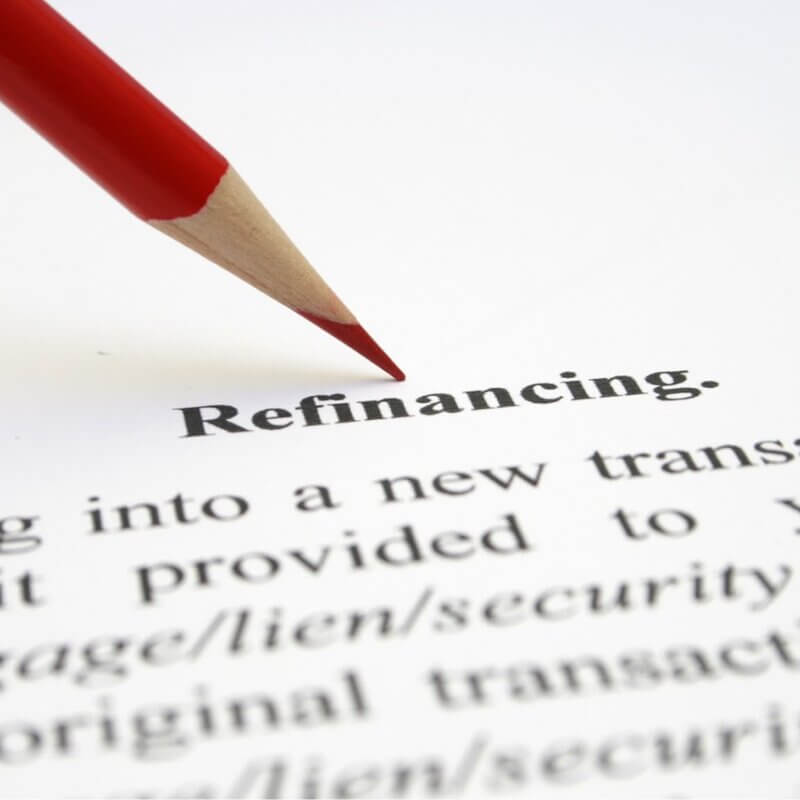 Decorative image. Red colored pencil pointing to the word Refinancing on a document.